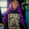 Person with purple hair wearing a black t-shirt with 'RAGE' graphic design.