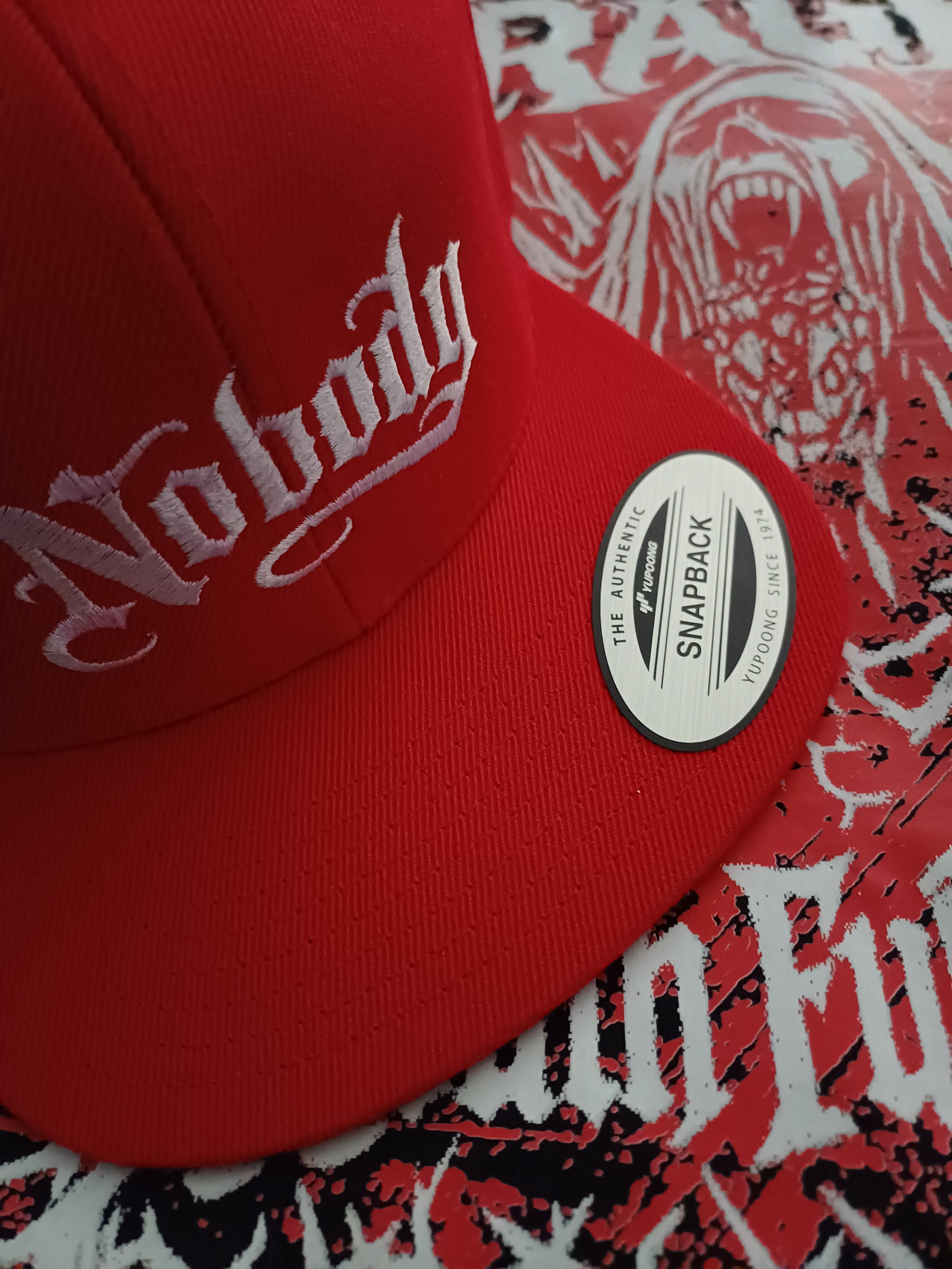 Red cap with white text and a brand label on a patterned background