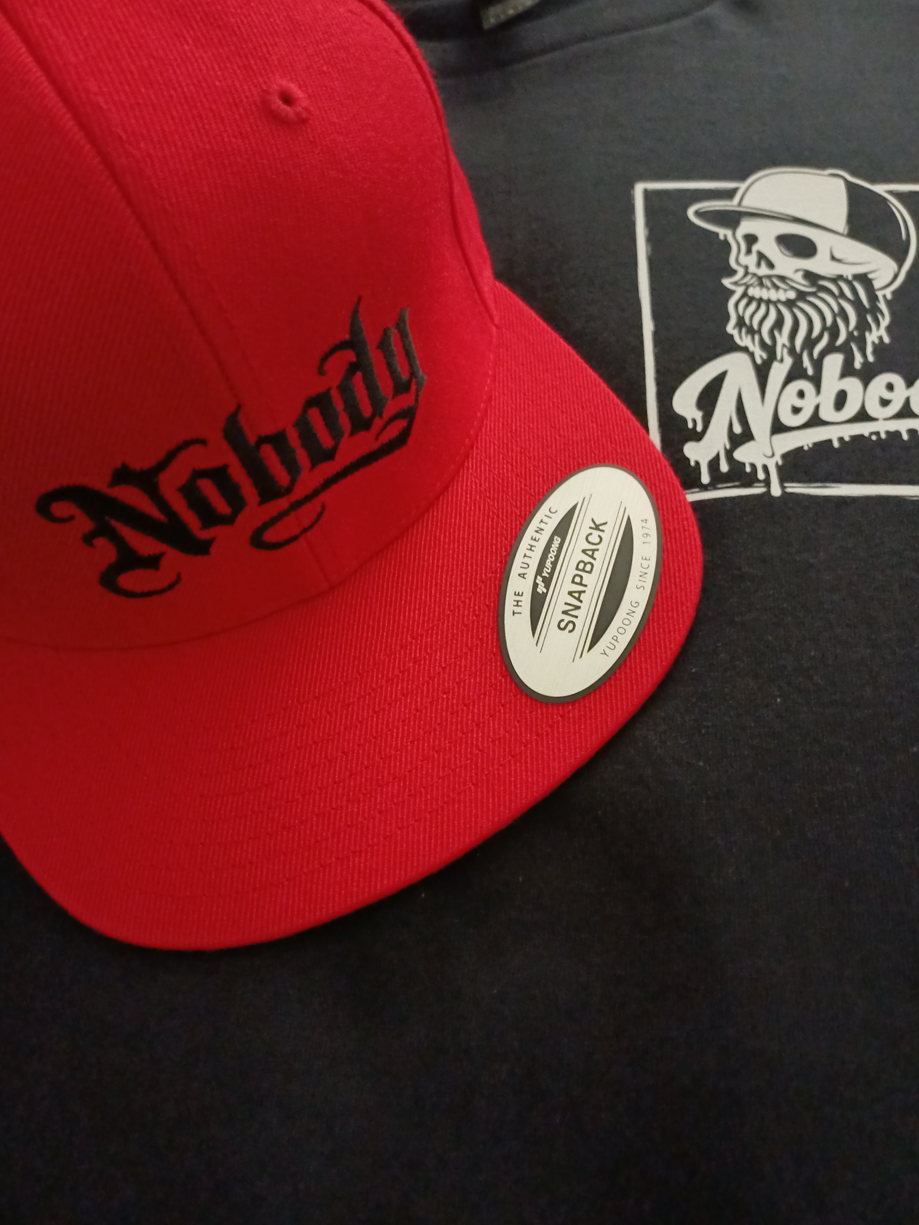 Red cap with black text and a visible brand logo on a dark background