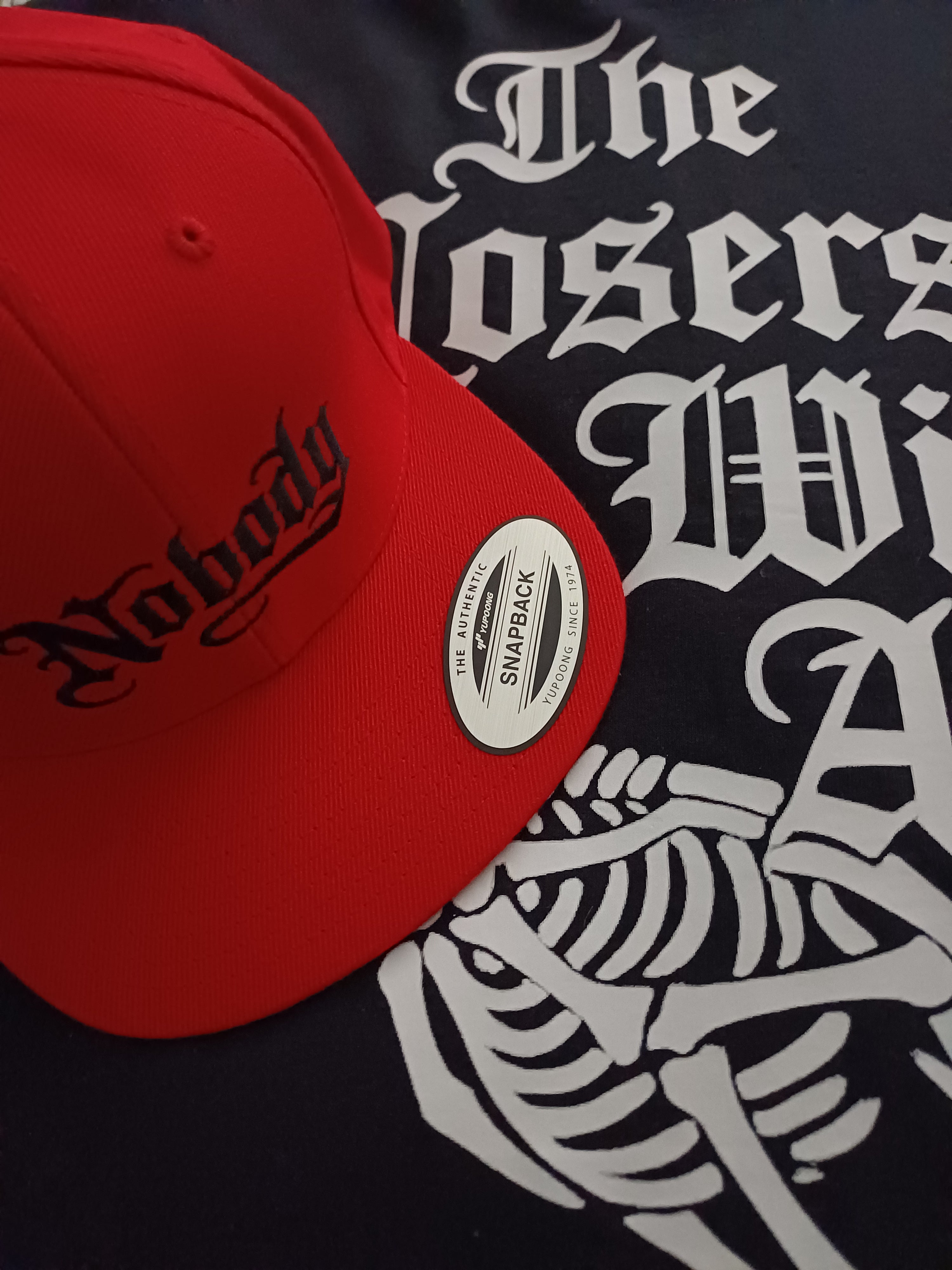 Red cap with black text on a black background with white graphic designs