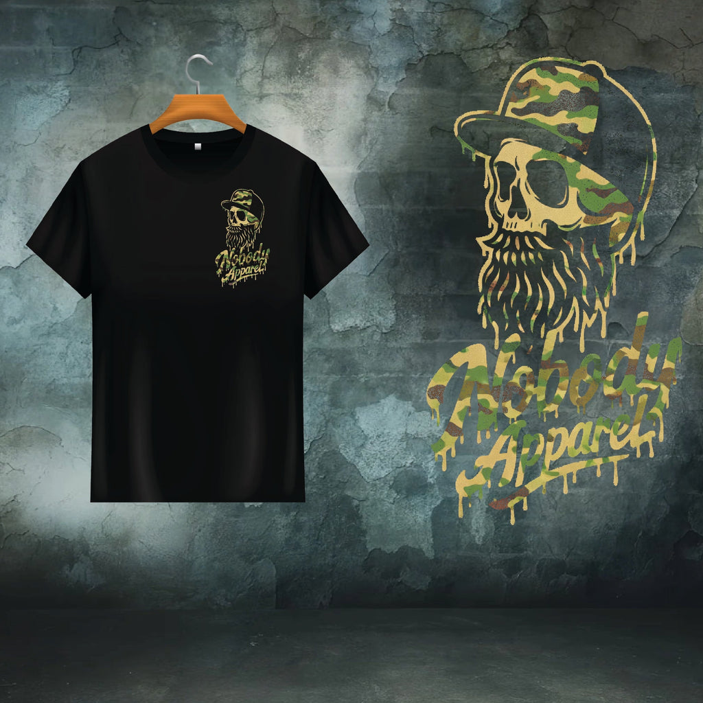 Black t-shirt with a graphic design of a skull with a beard and camouflage hat, displayed on a hanger against a textured green background.