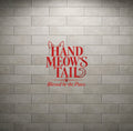 Red vinyl wall decal reading 'HAND MEOW'S TAIL' with 'Blessed be the Paws.' underneath, displayed on a gray brick wall background.